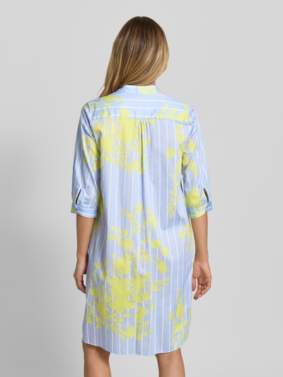 Frauenmodel trägt Knielanges Hemdblusenkleid mit kurzer Knopfleiste von Milano Italy aus Reine Baumwolle, Gerader-Schnitt, Knielänge, Hemdblusenkragen, 1/2-Arm, Rückenlänge bei Größe 36: 99 cm, Brustweite bei Größe 36: 51 cm, Ärmellänge bei Größe 36: 42 cm, blau mit gelbem Blumenmuster, lockere Struktur, Ganzkörperansicht Rückansicht.