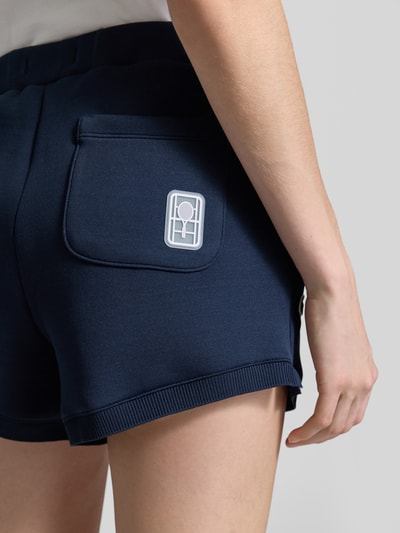 Frauenmodel trägt Regular Fit Sweatshorts mit Logo-Applikation von Lacoste, Optik: Unifarben, Materialverarbeitung: Sweat, Detailaufnahme.