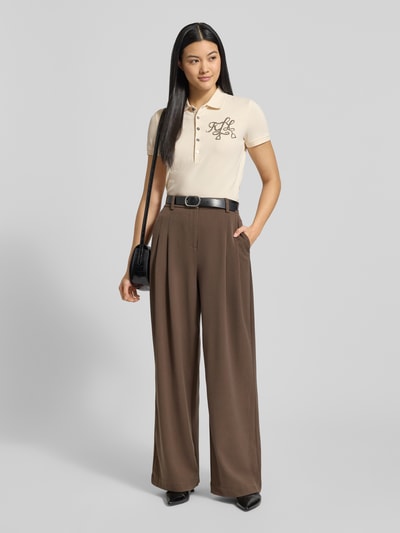 Frauenmodel trägt Slim Fit Poloshirt mit Logo aus Perlen Modell 'KIEWICK' von Lauren Ralph Lauren, cremefarben, Ganzkörperansicht von vorne.