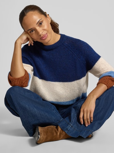 Frauenmodel trägt Relaxed Fit Pullover mit Woll-Anteil in Strick-Optik von MORE, farblich abgesetzt in Blau, Creme, Braun und Hellblau, Rundhalsausschnitt, 3/4-Arm, lockere Passform, Material-Mix, Ganzkörperansicht von vorne.