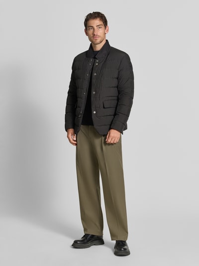 Męski model nosi Regular Fit Jacke in Stepp-Optik Model 'Joen' od Tiger of Sweden, czarny kolor, stójka, kieszenie z patką, listwa guzikowa, długość tyłu w rozmiarze 50: 70 cm, szerokość ramion w rozmiarze 50: 47 cm, szerokość klatki piersiowej w rozmiarze 50: 51 cm, długość rękawów w rozmiarze 50: 64 cm, całopostaciowy widok z przodu.