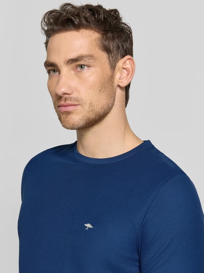Mężczyznamodel nosi Regular Fit T-Shirt mit Logo-Stitching von Fynch-Hatton, bawełna, krój regular fit, okrągły dekolt, długość tyłu w rozmiarze M: 68 cm, kolor niebieski, gładka faktura, zbliżenie na górną część ciała.