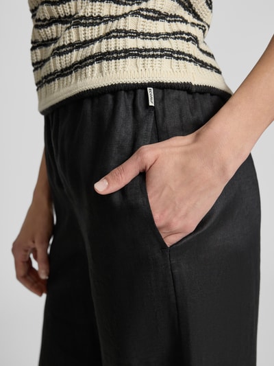 Frauenmodel trägt Wide Leg Leinenhose mit elastischem Bund Modell 'MOSSI' von ECOALF in Schwarz, reine Leinenstruktur, Nahaufnahme Hüfte.