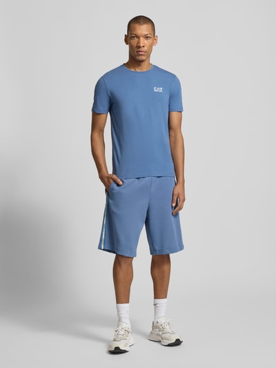 Männermodel trägt Sweatshorts mit Label-Details und Eingrifftaschen von EA7 Emporio Armani, Baumwoll-Mix, Relaxed-Fit, Ganzkörperansicht von vorne.