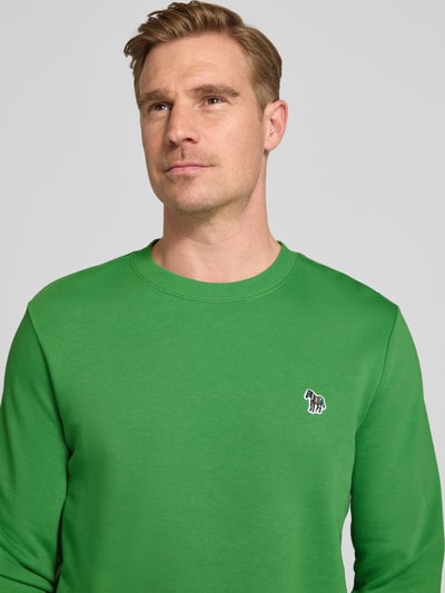 Männermodel trägt Regular Fit Sweatshirt mit Rundhalsausschnitt von PAUL SMITH in Grün aus Reiner Baumwolle mit Stitching, Nahaufnahme Oberkörper.