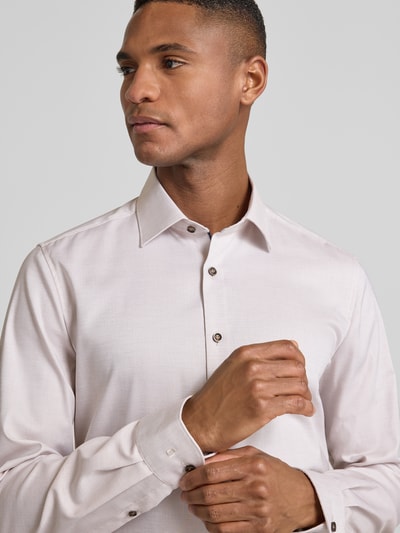 Männermodel trägt Slim Fit Businesshemd aus Baumwoll-Mix mit Kentkragen von OLYMP Level Five in Hellrosa, Nahaufnahme Oberkörper. Elastischer Stoff, durchgehende Knopfleiste, Langarm mit Sportmanschetten, glatte Textur.
