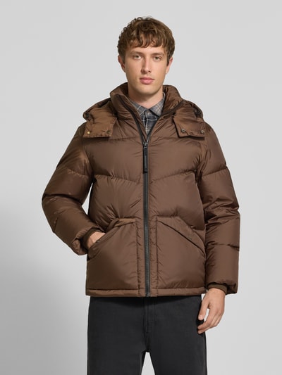 Männermodel trägt Regular Fit Daunenjacke mit Kapuzenkragen von Marc O'Polo DENIM in Braun, gesteppte Oberfläche, Ganzkörperansicht von vorne.