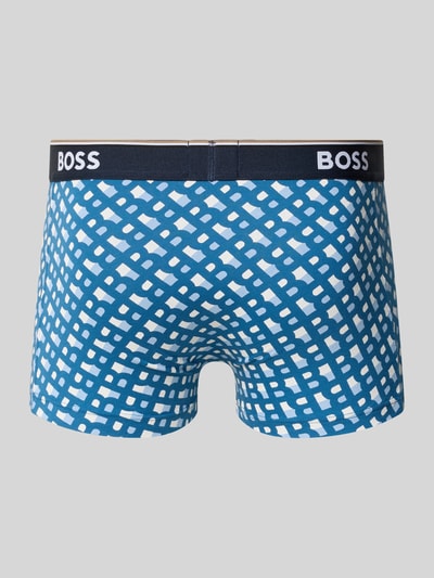 Männermodel trägt Trunks aus Baumwoll-Mix im 3er-Pack von BOSS in Blau mit weißem Allover-Muster, elastischer Label-Bund, Ganzkörperansicht Rückansicht.
