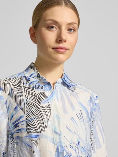 Kobiece modelka nosi Relaxed Fit Leinenbluse mit 3/4-Arm Modell 'Clay' od TONI z czystego lnu, wzór allover, kołnierz koszulowy, jasnoniebieskie i czarne liściaste wzory, tekstura lnu, zbliżenie na górną część ciała