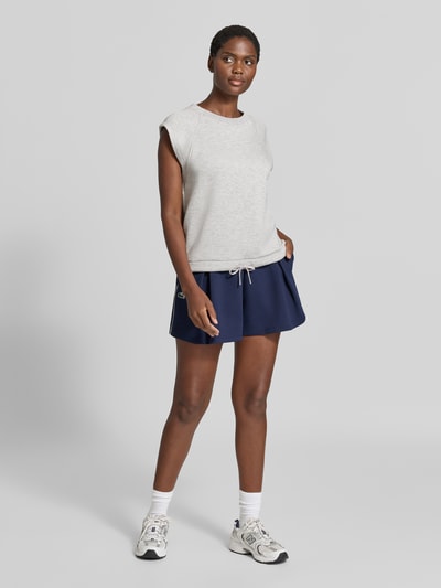 Kobiece modelka nosi Relaxed Fit Sweatshirt aus Viskose-Mix Model 'Salome' von VARLEY, jasnoszara bluza, elastyczna mieszanka wiskozy, krój relaxed fit, okrągły dekolt, bez rękawów, pas z tunelem, pełny widok z przodu.