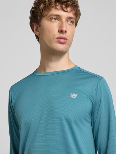 Männermodel trägt Funktionsshirt mit Rundhalsausschnitt und Logo von New Balance in Blau, Regular Fit, Longsleeve, Nahaufnahme Oberkörper.