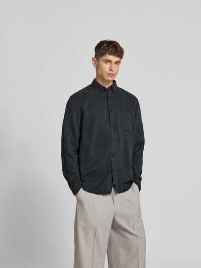 Männermodel trägt Regular Fit Freizeithemd aus Lyocell von Filippa K in Schwarz, langärmelig, mit Brusttasche, Ganzkörperansicht von vorne.