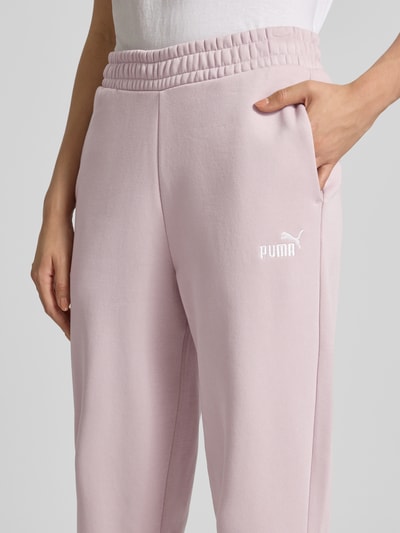 Vrouwenmodel draagt Sweatpants mit Label-Stitching und elastischem Bund van PUMA in lichtroze katoenmix, relaxed fit, labelstitching, elastische band, binnenbeenlengte maat S 74 cm, detailopname heupen en bovenbeen