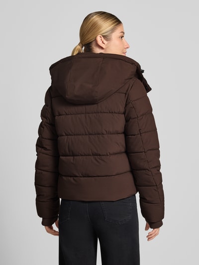 Frauenmodel trägt Jacke mit Daumenloch und Kapuze von NAUTGÅRD in Dunkelbraun, gerader Schnitt, Steppstruktur, detailreiche Texturen, Ganzkörperansicht Rückansicht. Rückenlänge 58 cm, Schulterbreite 40 cm, Brustweite 48 cm, Ärmellänge 65 cm.