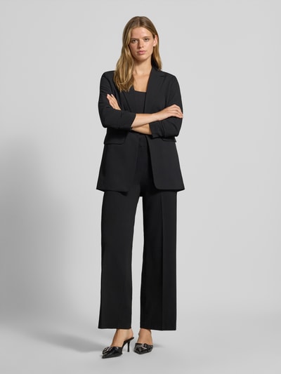 Frauenmodel trägt Regular Fit Weite Hose mit Bügelfalten Modell 'KALINA' von ONLY, schwarze Farbe, glatte Struktur, Ganzkörperansicht von vorne, Damen Weite Hose von ONLY.