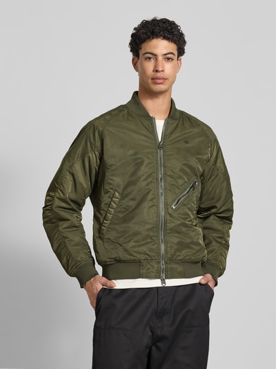 Mannenmodel draagt Regular Fit Bomberjacke met Stehkragen van G-Star Raw in olijfgroen, tweeweg-ritssluiting, logo-appliqué, ritszak, elastische boorden, medium lengte 61 cm, schouderbreedte 40 cm, borst 45 cm, mouwlengte 68 cm, voorkant hele lichaam.