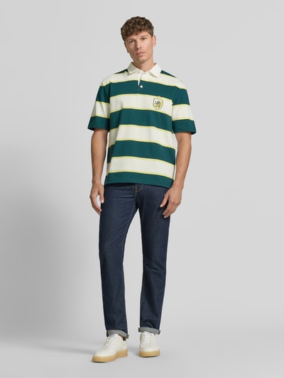 Męskimodel nosi Regular Fit Poloshirt mit Label-Stitching od MCNEAL z bawełny, listwa guzikowa, długość tyłu w rozmiarze M: 66 cm, pasiasty wzór, zielony i kremowy, krój regular fit, widok na całe ciało z przodu.