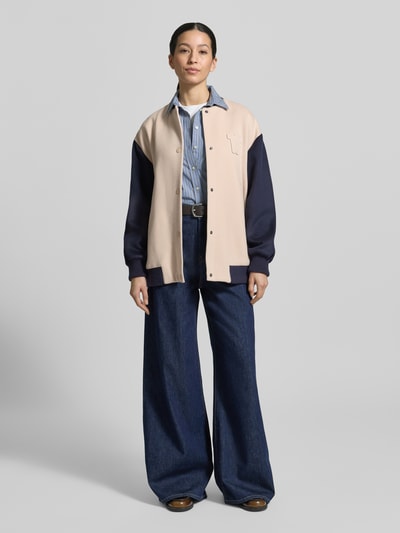 Vrouwenmodel draagt Relaxed Fit College-jack uit scheerwolmix model 'ELLISSE' van Weekend Max Mara, effen en tweekleurige look, lange mouw, drukknopen, collegekraag, applicatie met labelstitching, geribde mouwboord en rompzoom, zij-steekzakken, comfort fit, mix van scheerwol, geheelopname van voren.
