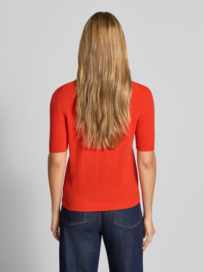 Frauenmodel trägt Poloshirt aus reiner Wolle von Stefanel in Rot, taillierte Passform, glatte Textur, Ganzkörperansicht Rückansicht.