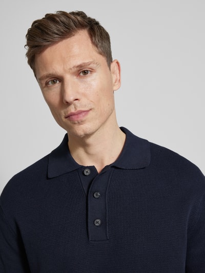 Männermodel trägt Relaxed Fit Poloshirt aus reiner Baumwolle Modell 'DANE' von SELECTED HOMME, unifarben, Strickoptik, Nahaufnahme Oberkörper.