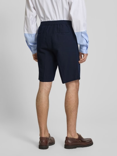 Männermodel trägt dunkelblaue Straight Fit Shorts aus Leinen-Mix von Filippa K, elastischer Bund, Eingriff- und Gesäßtaschen, Ganzkörperansicht Rückansicht