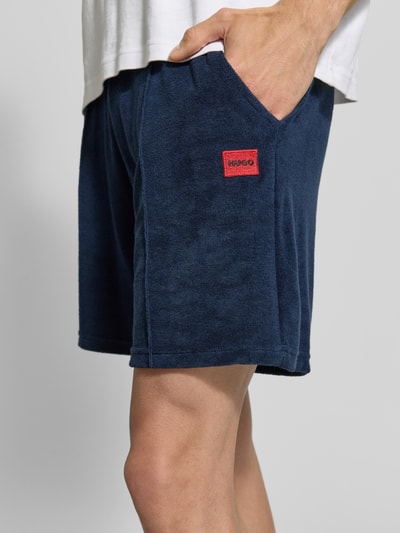 Männermodel trägt Regular Fit Sweatshorts aus Baumwoll-Mix Modell 'TERRANCE' von HUGO, Optik: Unifarben, Label-Patch, Nahaufnahme Oberschenkel.