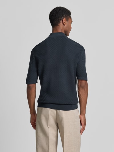 Männermodel trägt Regular Fit Poloshirt mit Strukturmuster Modell 'ARAAWEN' von Tiger Of Sweden aus bawełna, ciemny kolor, kołnierzyk polo, krótki rękaw, listwa guzikowa, długość tyłu 68 cm w rozmiarze M, długość rękawów 28 cm, Ganzkörperansicht Rückansicht