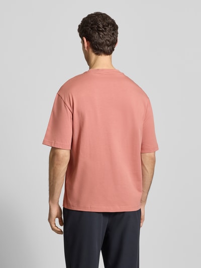 Männermodel trägt Relaxed Fit T-Shirt aus reiner Baumwolle Modell 'RELEXASPEN' von SELECTED HOMME in unifarbenem Rosa, Feinrippstruktur, Ganzkörperansicht Rückansicht.