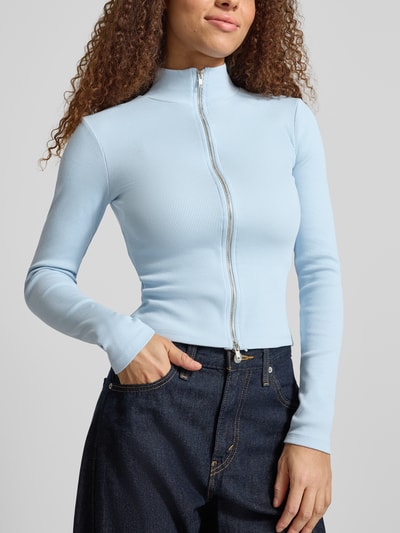 Frauenmodel trägt Slim Fit Jacke mit Stehkragen von Gina Tricot aus elastischem Baumwoll-Mix in Hellblau, Zweiwege-Reißverschluss, Nahaufnahme Oberkörper.