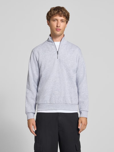 Männermodel trägt Regular Fit Sweatshirt mit Baumwoll-Anteil Modell 'Bradley' von JACK & JONES in Hellgrau, Ganzkörperansicht von vorne, Material-Mix, Troyer-Kragen, Rückenlänge 68 cm, Ärmellänge 66 cm.