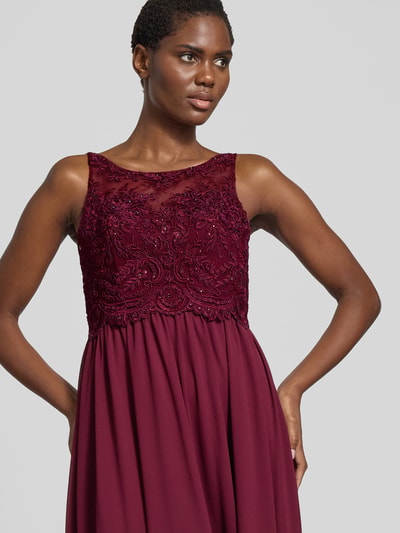 Frauenmodel trägt Abendkleid mit Ziersteinen und floralen Stickereien von LAONA in Bordeaux, taillierte Passform, Rundhalsausschnitt, Doppellagiger Rockteil, Nahaufnahme Oberkörper.