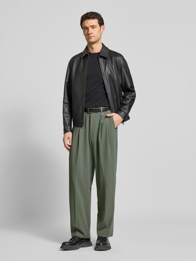 Männermodel trägt Stoffhose mit Label-Detail von Antony Morato in Grün, Material-Mix mit Viskose-Anteil, lockerer Schnitt, Bundfalten, Französische Eingrifftaschen, Gesäßtaschen, elastischer Bund, Ganzkörperansicht von vorne.