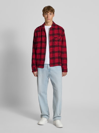 Męski model nosi Regular Fit Freizeithemd mit Kentkragen od REVIEW, bawełna, kieszeń na piersi, czerwono-czarna krata, widok z przodu całej sylwetki.
