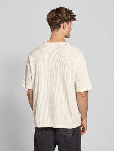 Męski model nosi Strickshirt mit Strukturmuster und Label-Stitching od Pegador, bawełna, krój relaxed fit, okrągły dekolt, długość tyłu w rozmiarze M: 71 cm, kremowy kolor, fakturowana powierzchnia, widok całej sylwetki z tyłu.