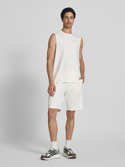 Männermodel trägt Bermudas mit elastischem Bund und Label-Stitching von CHAMPION, Baumwoll-Mix, Regular Fit, weiß, Ganzkörperansicht von vorne.