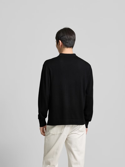 Männermodel trägt schwarzen Pullover aus reiner Lanawolle von Officine Générale, elastische Ärmelabschlüsse, Rückenansicht, Ganzkörperansicht Rückansicht.