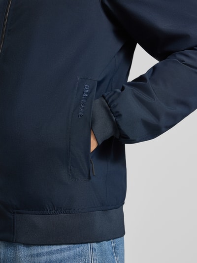 Männermodel trägt Regular Fit Jacke mit Stehkragen Modell 'Alvin' von Didriksons in Dunkelblau, Reißverschluss, Nahaufnahme Oberkörper.