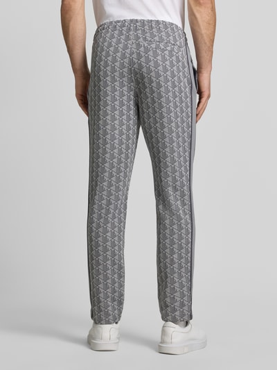 Männermodel trägt Regular Fit Sweathose mit Baumwoll-Anteil von Lacoste, grau gemustert mit grafischem Muster, Ganzkörperansicht Rückansicht. Herren Sweathose von Lacoste