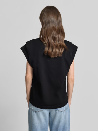 Kobieta nosi T-Shirt z drapowaniami model 'PIO' od Bash, czarna bawełna, krój regular fit, okrągły dekolt, widok całej sylwetki z tyłu.