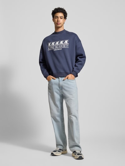 Männermodel trägt Sweatshirt mit Label-Print von Another Cotton Lab in Dunkelblau aus Baumwoll-Mix mit Rundhalsausschnitt, Lockerer-Schnitt, gerippte-Abschlüsse, Ganzkörperansicht von vorne.