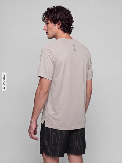Męski model nosi Regular Fit T-Shirt mit Aero-FIT-Technologie Modell 'STRIDE' od Nike Training, jasnoszary, tekstura gładka, całkowita tylna perspektywa, KI-modifiziertes Bild.