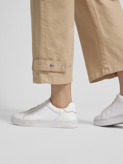 Frauenmodel trägt Wide Fit Hose mit Eingrifftaschen von Marc Cain aus elastischem Baumwoll-Mix in Beige, Detailaufnahme Beinabschluss.