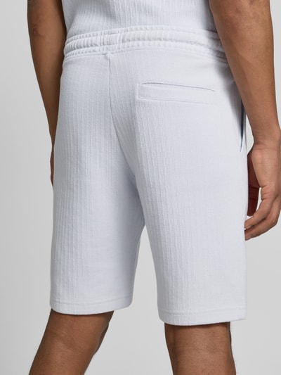 Männermodel trägt Regular Fit Shorts mit Tunnelzug von MCNEAL aus weißem Baumwoll-Mix mit Stretch-Anteil, Gesäßtasche, Ganzkörperansicht Rückansicht.