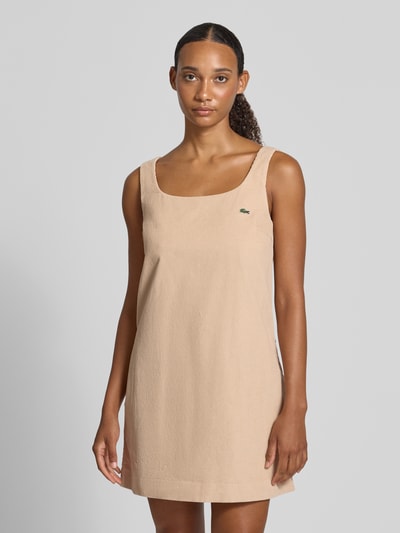 Vrouwenmodel draagt Slim Fit vrijetijdsjurk uit puur katoen van Lacoste in beige met gladde textuur, geheel vooraanzicht van bovenlichaam. Context: Dames vrijetijdsjurk van Lacoste.