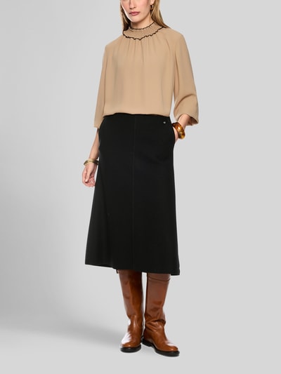 Frauenmodel trägt Midirock aus Schurwolle mit Reißverschluss von Marc Cain in Schwarz, A-Linie, Label-Detail, Ganzkörperansicht von vorne.