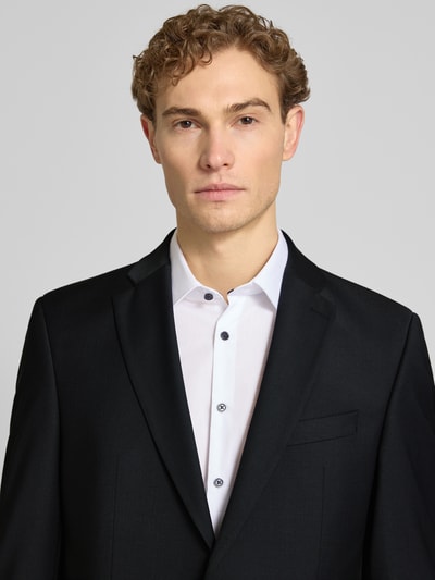 Männermodel trägt Slim Fit Anzug mit 2-Knopf-Sakko Modell 'Grant' von Pierre Cardin, schwarzer Stoff, Nahaufnahme Oberkörper.