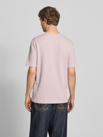 Männermodel trägt T-Shirt mit Strukturmuster und Label-Stitchings von CHAMPION in hellem Pastell, Baumwoll-Mix, Regular Fit, Ganzkörperansicht Rückansicht.