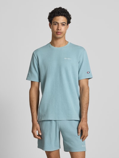 Männermodel trägt T-Shirt mit Strukturmuster und Label-Stitchings von CHAMPION, hellblau, Regular Fit, Oberteil aus Baumwoll-Mix, Nahaufnahme Oberkörper.