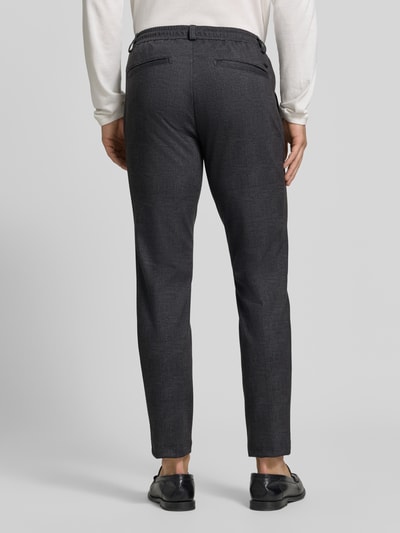 Männermodel trägt dunkelgraue, weite Hose Tapered Fit Jogpants aus reiner Baumwolle Modell 'Phil' von Brax, Herrenmode, Ganzkörperansicht Rückansicht.