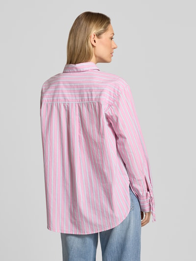 Frauenmodel trägt Oversized Hemdbluse aus reiner Baumwolle von Tom Tailor Denim in mehrfarbig gestreifter Popeline, Rückenpasse mit Logo-Patch, Ganzkörperansicht Rückansicht.